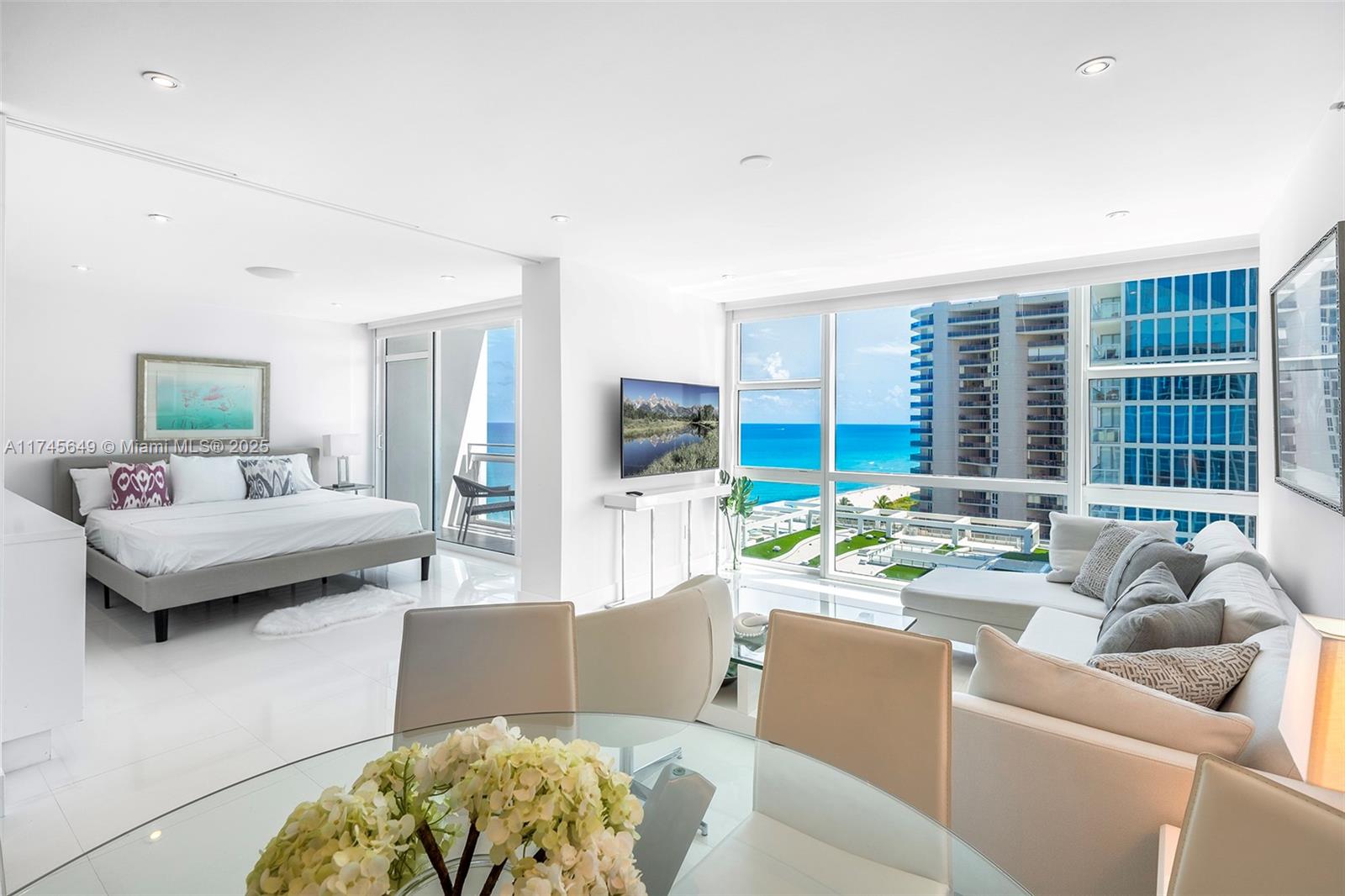 A bright, open-concept living and bedroom area features white floors, modern furniture, and ocean views — 6801 Collins Ave # 1206, Miami Beach FL 33141, MIAMI BEACH, FL