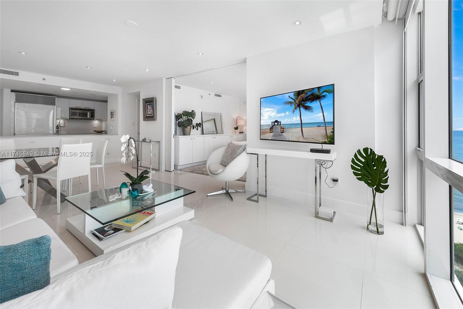 A bright, modern living room features white tile floors, a glass coffee table, and ocean views — 6801 Collins Ave # 1206, Miami Beach FL 33141, MIAMI BEACH, FL