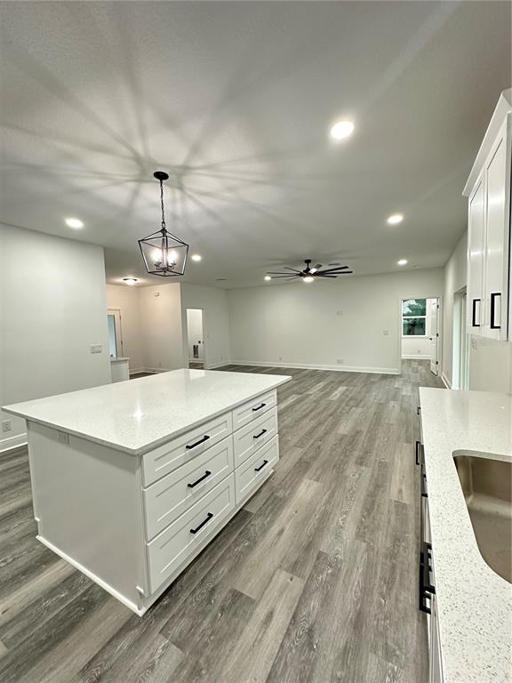 A kitchen with a white island, quartz countertops, and light wood-look flooring — 13311 MIDWAY AVENUE, ASTATULA, FL