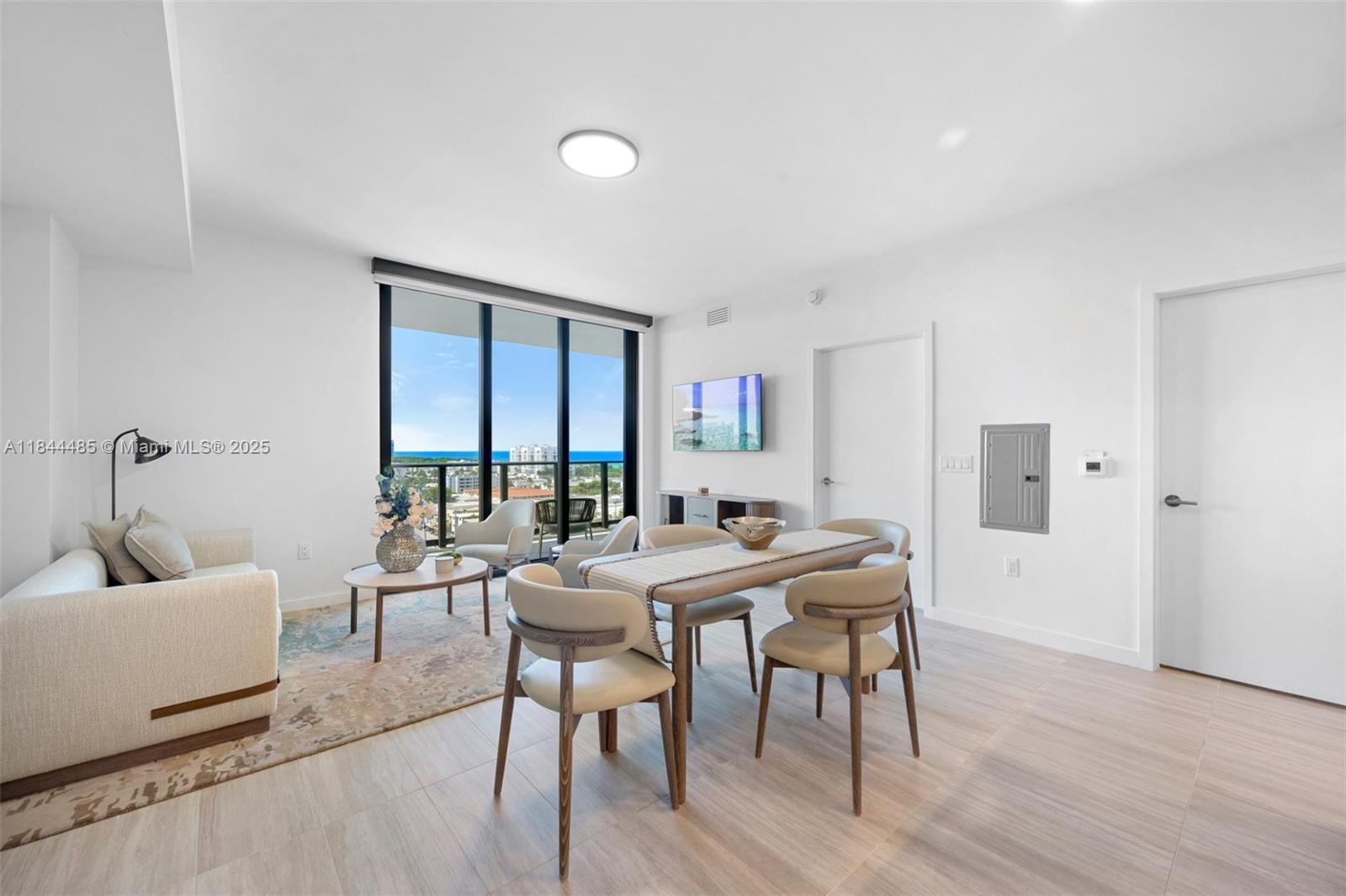 A modern living and dining area features light wood floors, white walls, and ocean views — 580 72nd St # 1009, Miami Beach FL 33141, MIAMI BEACH, FL