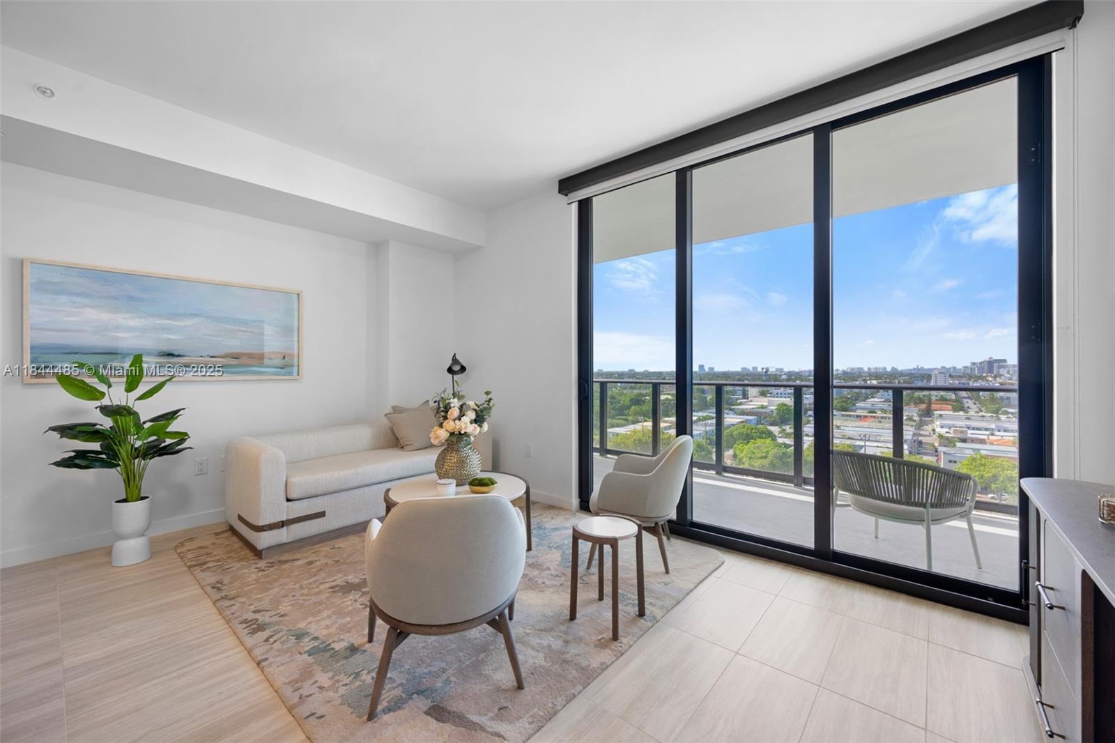 A modern living room features a sofa, armchairs, and a balcony with city views — 580 72nd St # 1009, Miami Beach FL 33141, MIAMI BEACH, FL