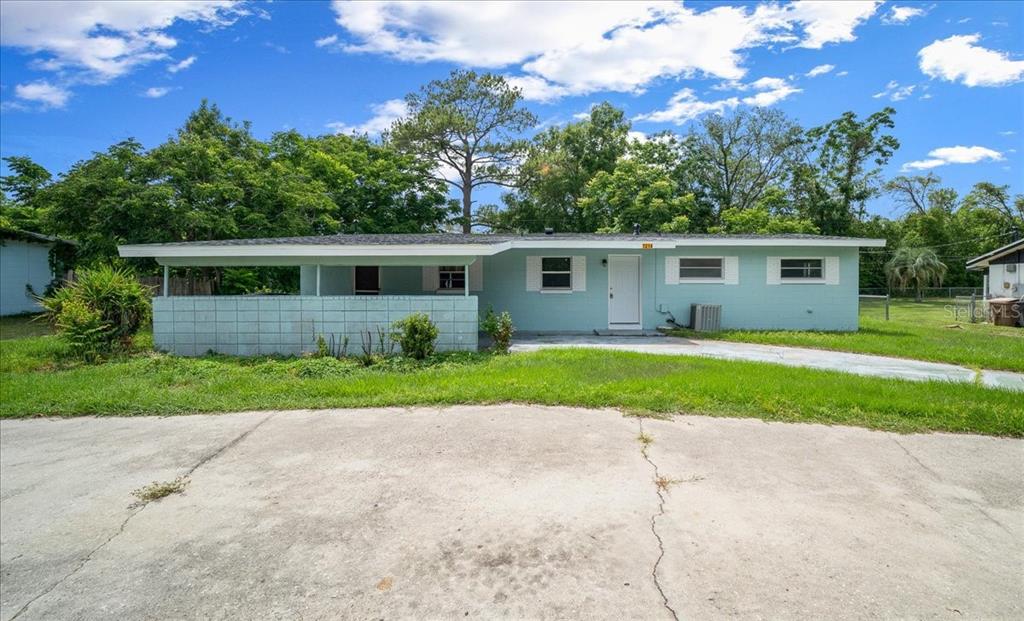 A single-story light blue house features a flat roof, a carport, and a concrete driveway — 1214 SE 36TH AVENUE, OCALA, FL