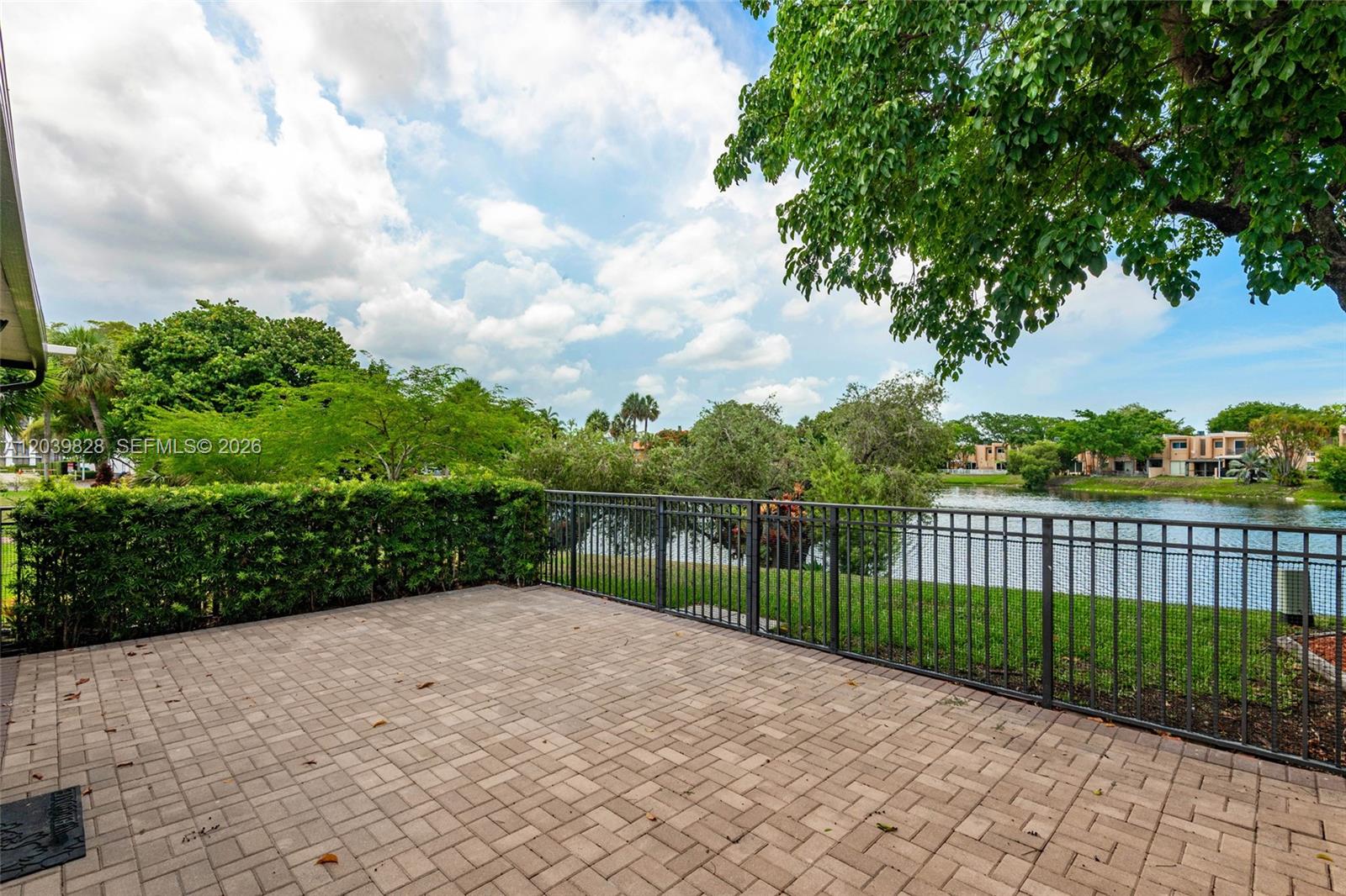 A screened-in patio features light-colored stone tile flooring and a view of a lake — 6653 SW 140th Ave # 6653, Miami FL 33183, MIAMI, FL