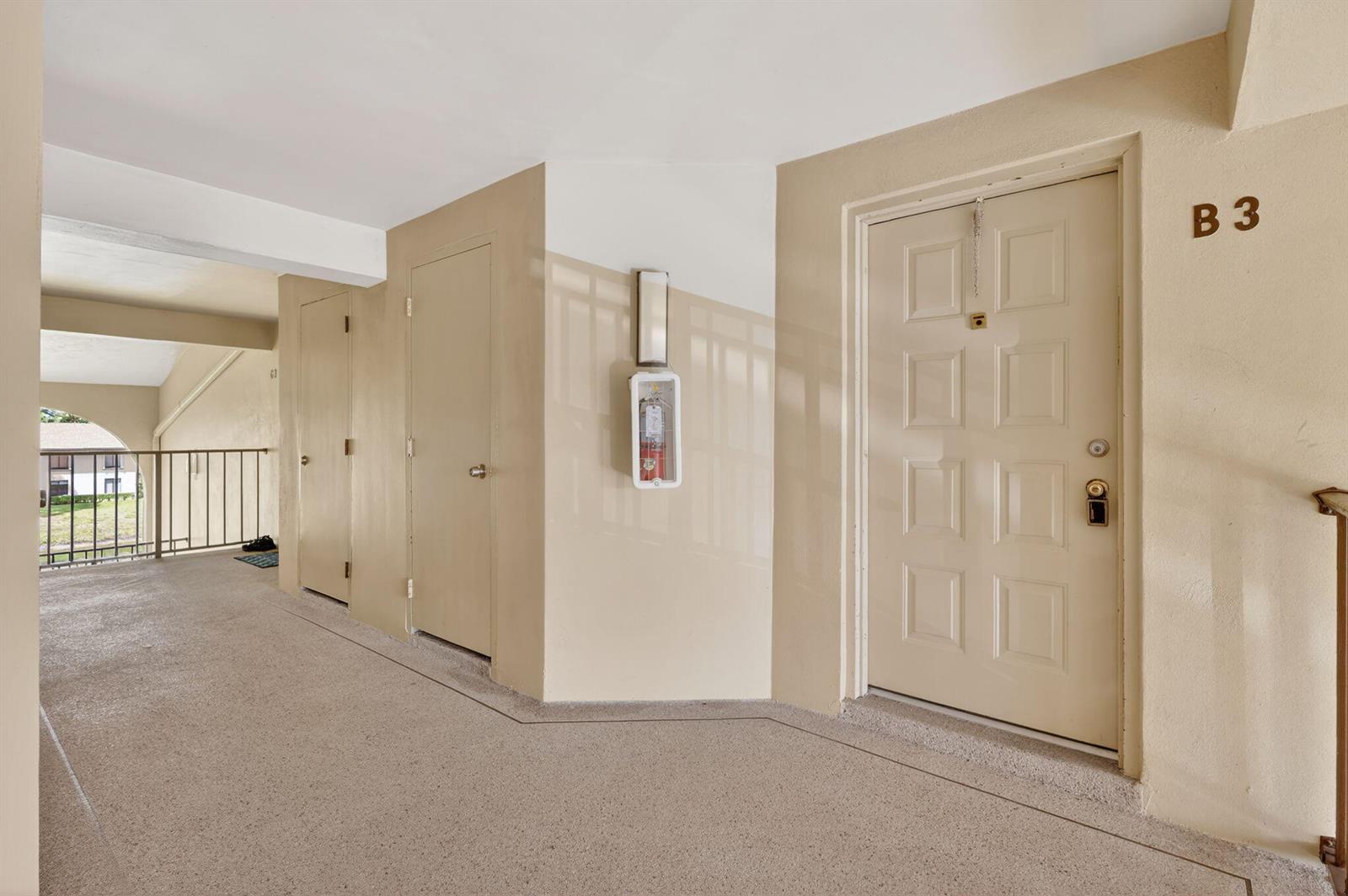 An outdoor apartment hallway features a beige door marked B3, a fire extinguisher, and railings — 624 Sea Pine Way # B3, FL 33415, FL
