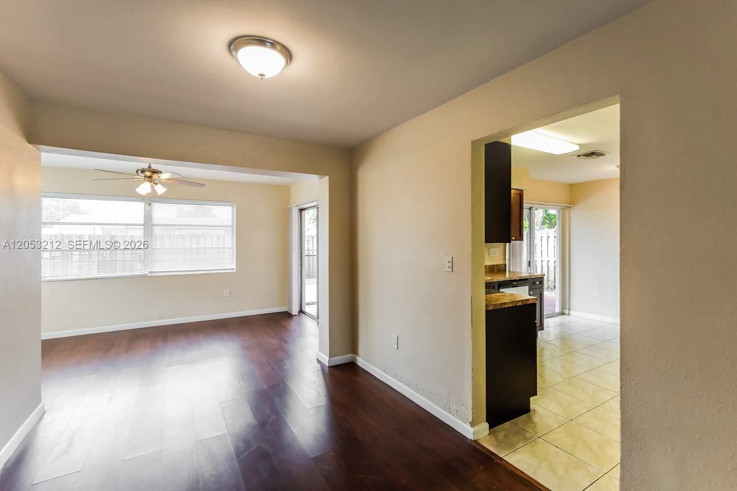 A living area with dark wood floors leads into a kitchen with tiled flooring — SUNRISE, FL