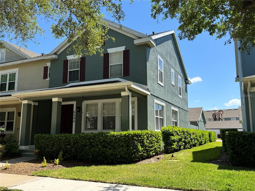 A two-story green house with a front porch and a manicured hedge — 8484 LEELAND ARCHER BOULEVARD, ORLANDO, FL