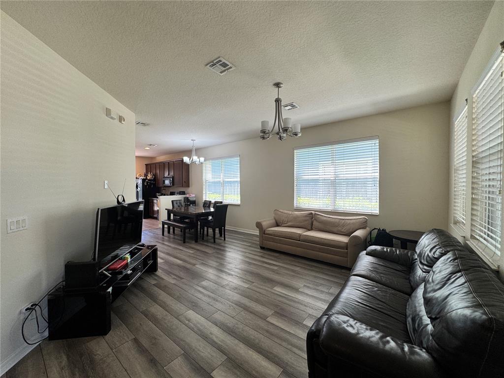 A living room with wood-look flooring, two sofas, and an adjacent dining area — 8484 LEELAND ARCHER BOULEVARD, ORLANDO, FL