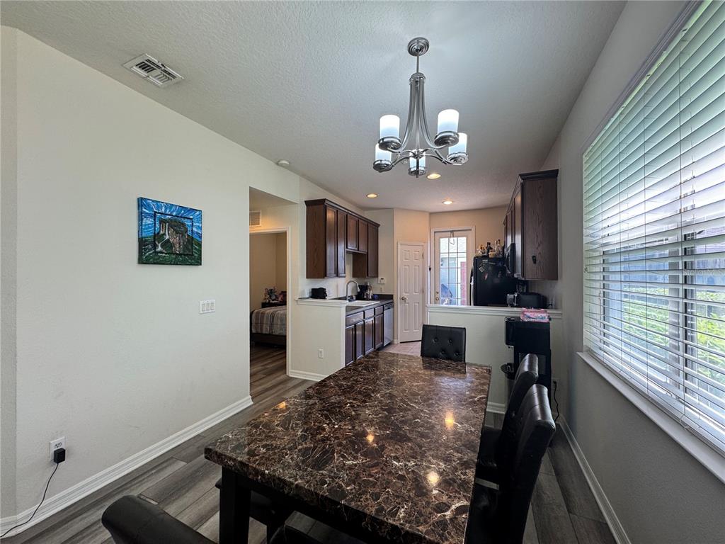 A dining area features a dark marble table, leather chairs, and a chandelier near a kitchen — 8484 LEELAND ARCHER BOULEVARD, ORLANDO, FL