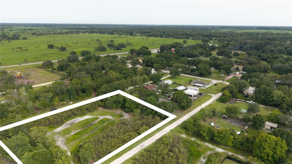 An aerial view shows a rectangular vacant lot outlined in white next to a rural road — NE 2ND TERRACE, OKEECHOBEE, FL