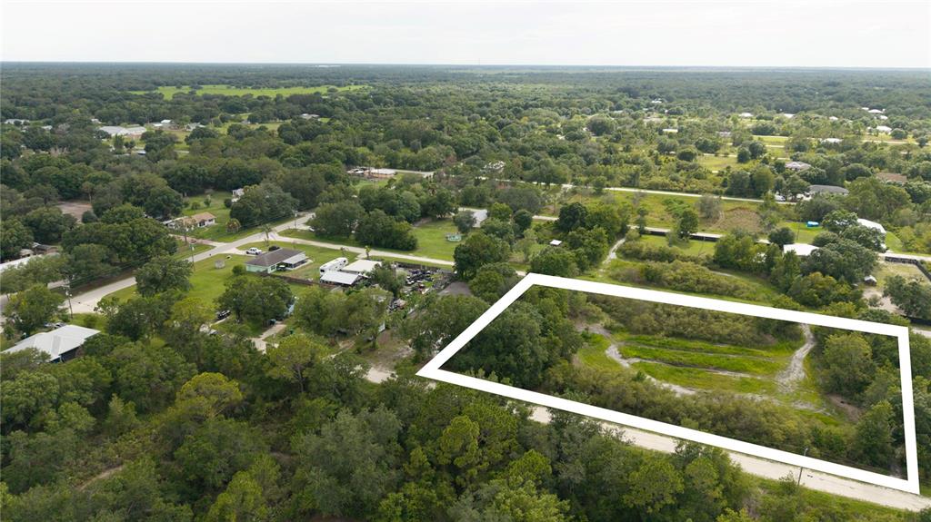 An aerial view shows a rectangular, undeveloped plot of land outlined in white — NE 2ND TERRACE, OKEECHOBEE, FL