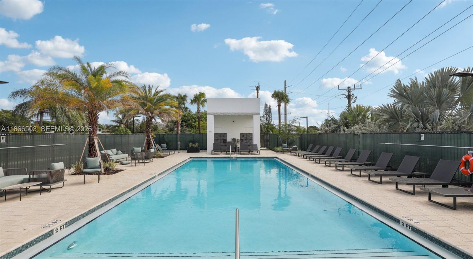 An outdoor rectangular swimming pool is surrounded by lounge chairs, palm trees, and a fence — 4465 Griffin Road # B5, Davie FL 33314, DAVIE, FL