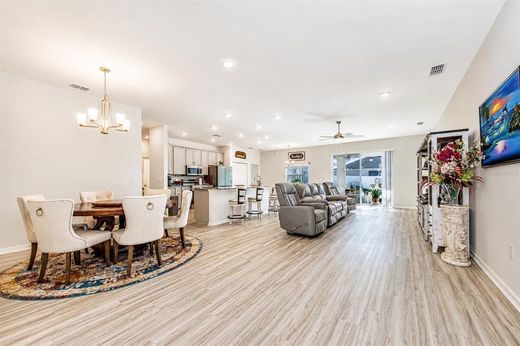 An open-concept living and dining area features light wood-look flooring and a modern kitchen — 1096 SANDPIPER LOOP, WINTER HAVEN, FL