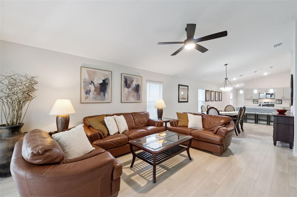 A living room with brown leather sofas, a coffee table, and an open kitchen area — 4015 GARDENIA AVENUE, HAINES CITY, FL