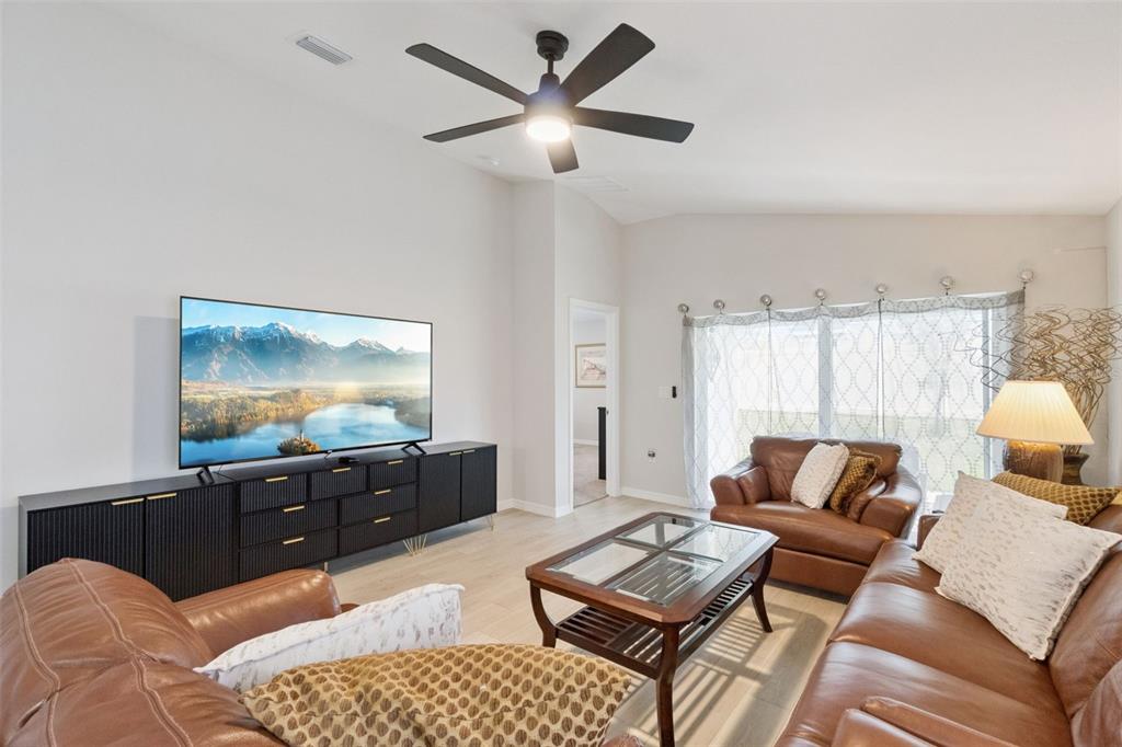 A living room features a black media console, leather furniture, and a ceiling fan — 4015 GARDENIA AVENUE, HAINES CITY, FL