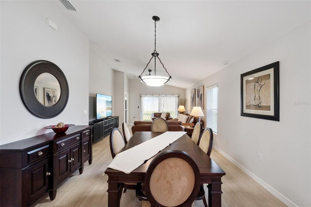 A dining room with a dark wood table, matching chairs, and a round wall mirror — 4015 GARDENIA AVENUE, HAINES CITY, FL