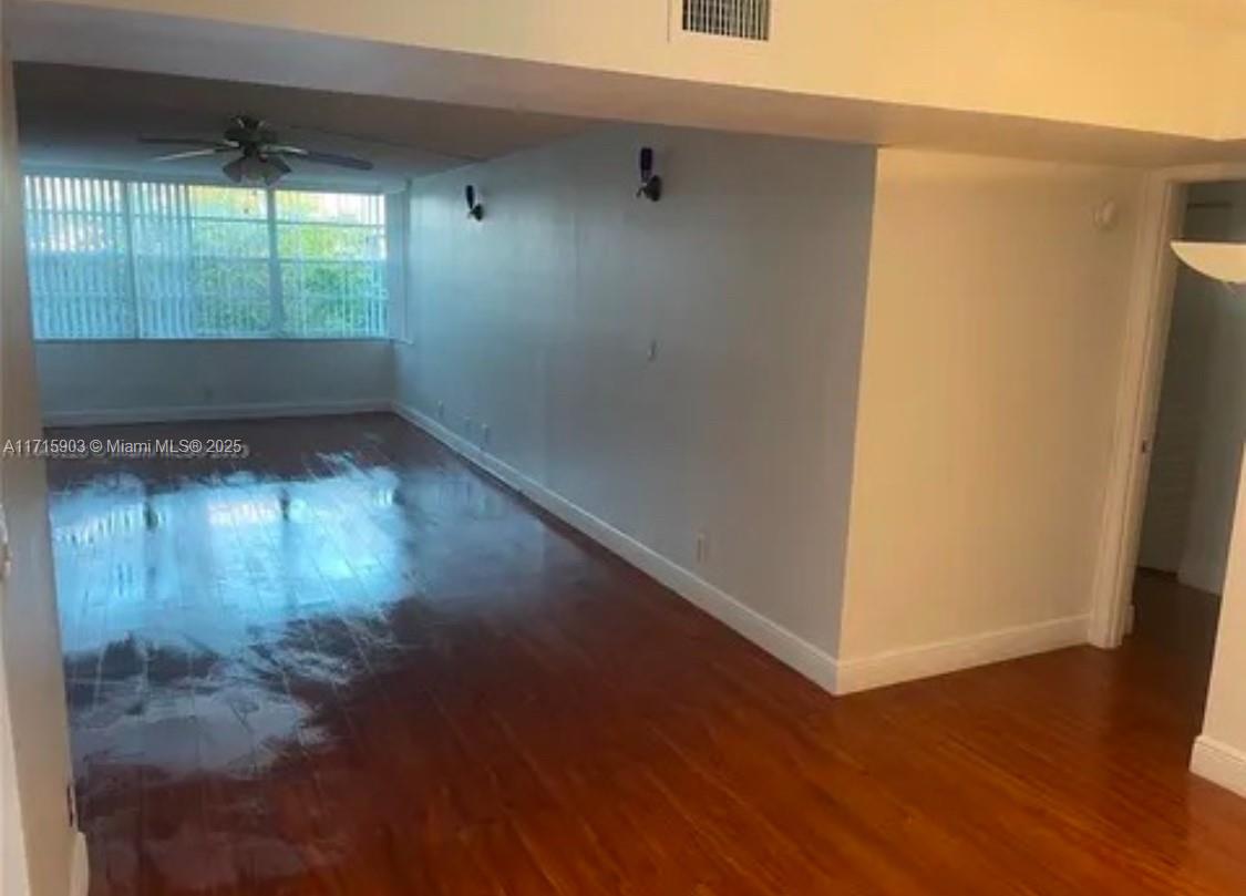 An empty room features hardwood flooring, light-colored walls, and a large window with blinds — 6700 Cypress Rd # 512, Plantation FL 33317, PLANTATION, FL