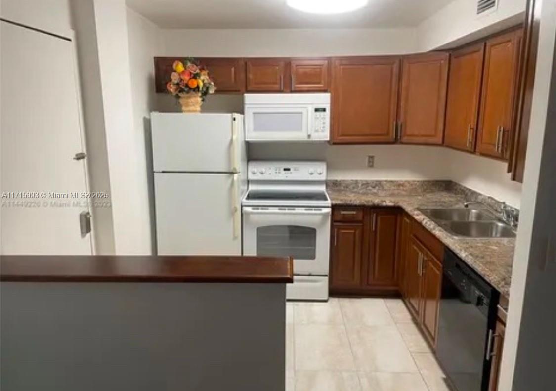 A kitchen features wood cabinets, white appliances, a double sink, and a breakfast bar — 6700 Cypress Rd # 512, Plantation FL 33317, PLANTATION, FL