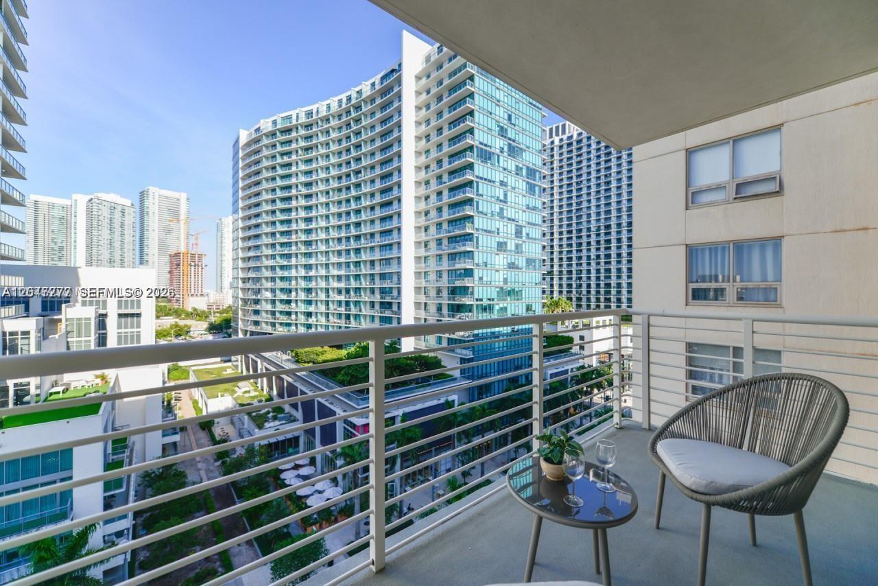 A balcony with a small table, two chairs, and a view of surrounding city skyscrapers — 3250 NE 1st Ave # 901, Miami FL 33137, MIAMI, FL