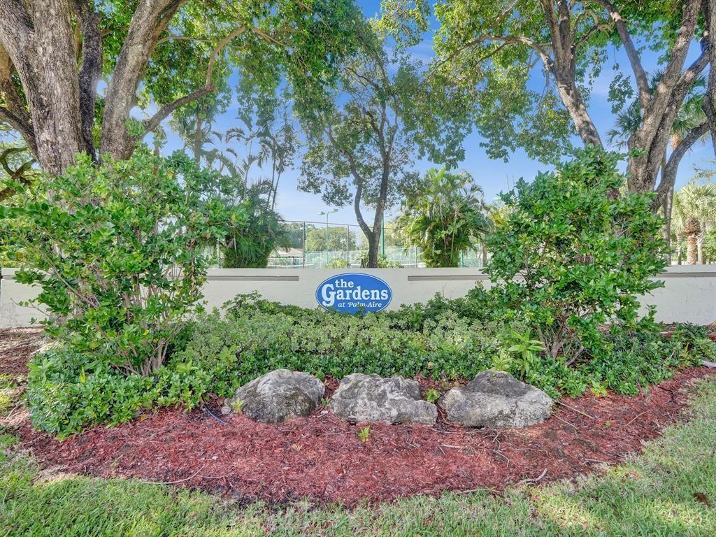 A stone sign for The Gardens at Palm-Aire sits in front of trees and landscaping — 715 Gardens Drive # 203, Pompano Beach FL 33069, POMPANO BEACH, FL
