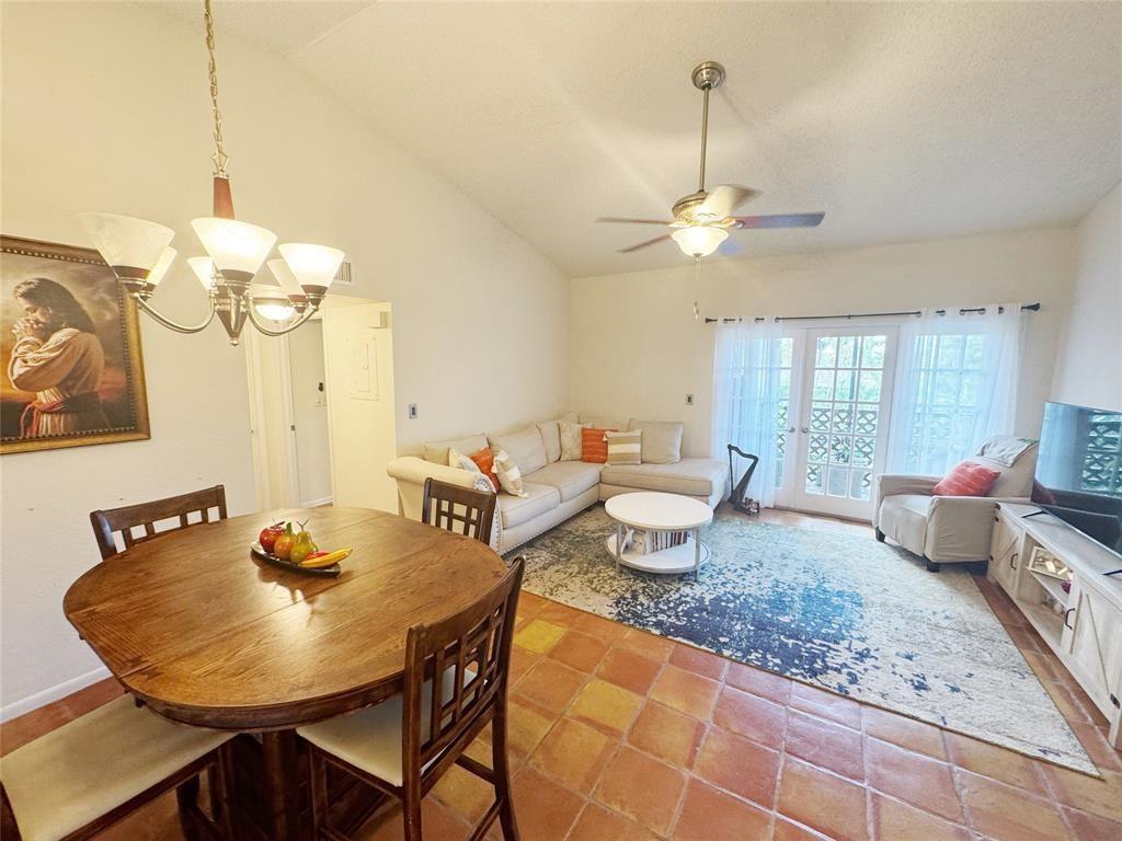 A dining area with a wooden table sits adjacent to a living room with tile floors — 715 Gardens Drive # 203, Pompano Beach FL 33069, POMPANO BEACH, FL