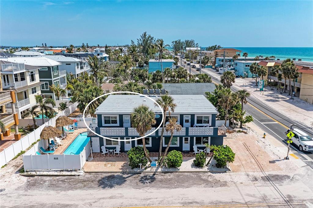 An aerial view shows the exterior of a two-story building with a pool and palm trees — 101 25TH STREET N UNIT 3, BRADENTON BEACH, FL