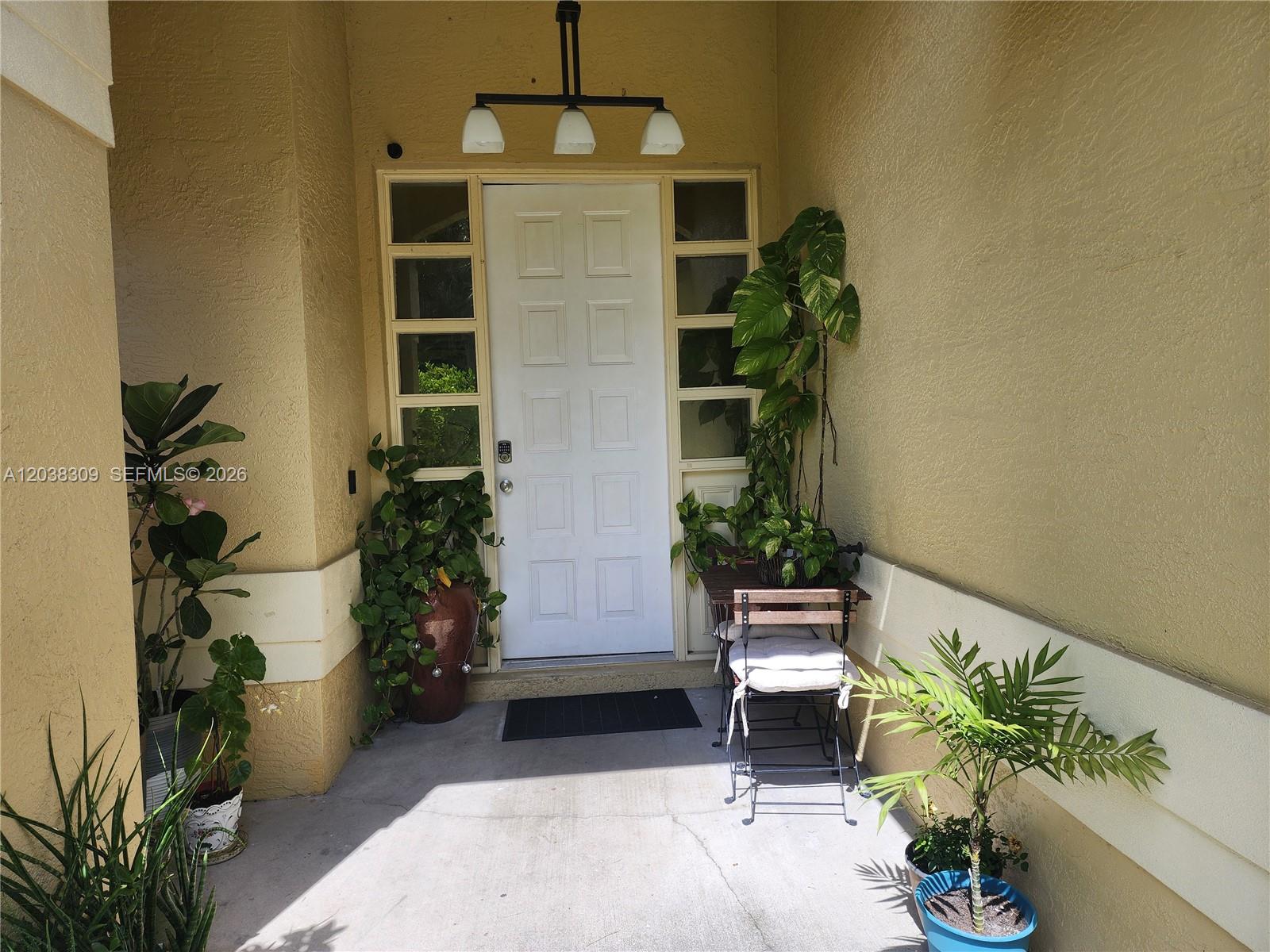 A white front door is flanked by side windows on a covered concrete porch — 111 2ND ST SE, Naples FL 34117, NAPLES, FL