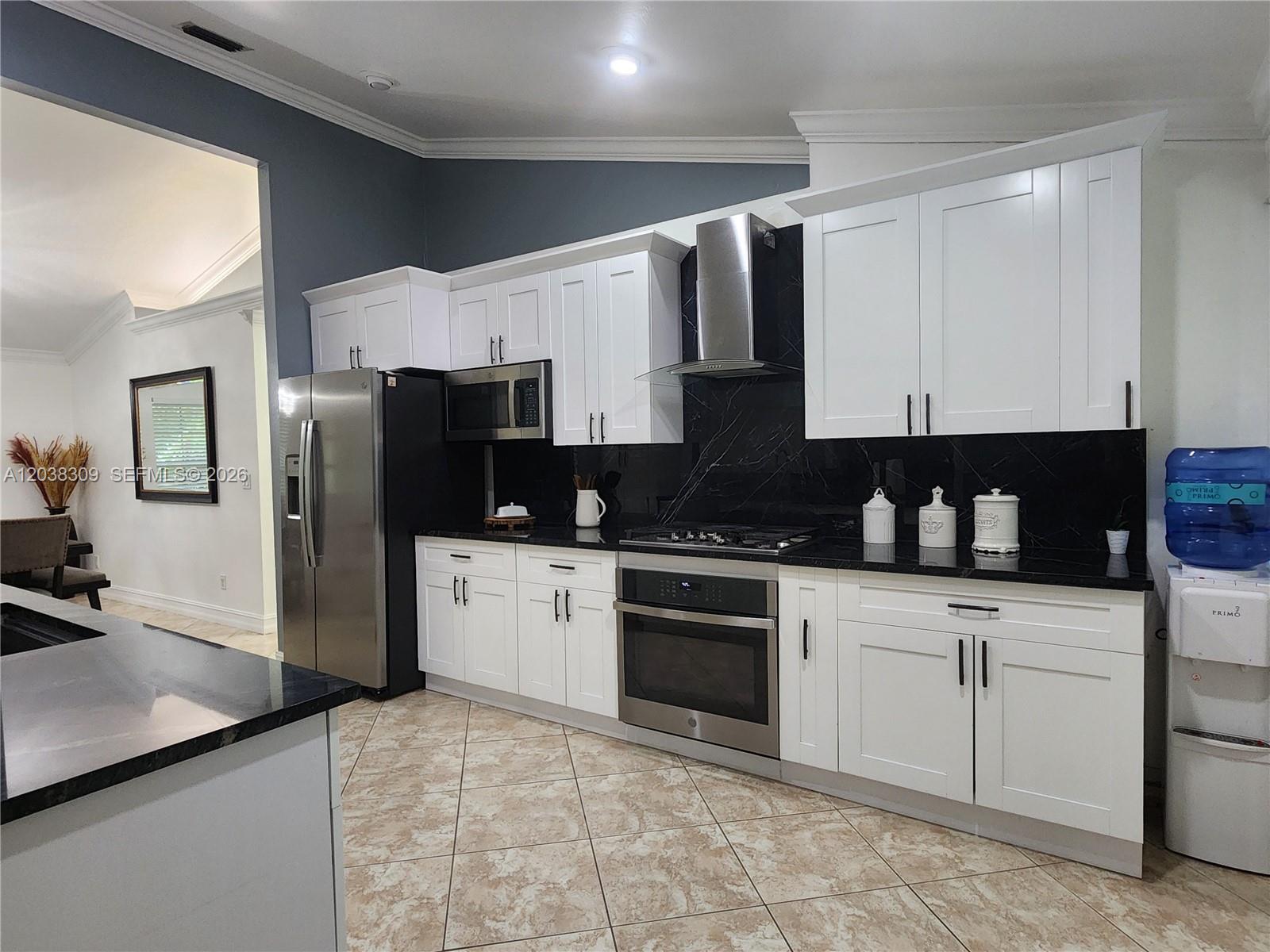 A kitchen features white cabinets, black countertops, a stainless steel oven, and a tile floor — 111 2ND ST SE, Naples FL 34117, NAPLES, FL