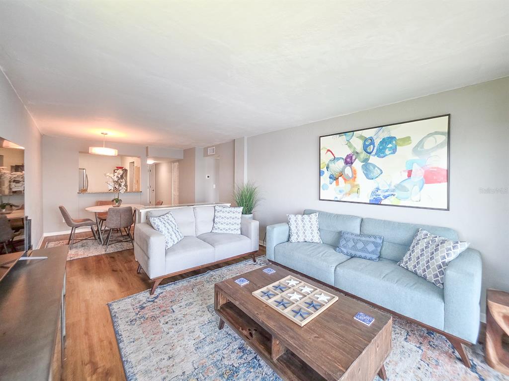 A living room with a light blue sofa, a wooden coffee table, and an adjacent dining area — 145 N HALIFAX AVENUE UNIT 711, DAYTONA BEACH, FL