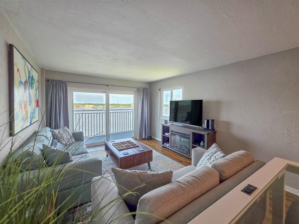 A living room features two sofas, a coffee table, a television, and a balcony view — 145 N HALIFAX AVENUE UNIT 711, DAYTONA BEACH, FL