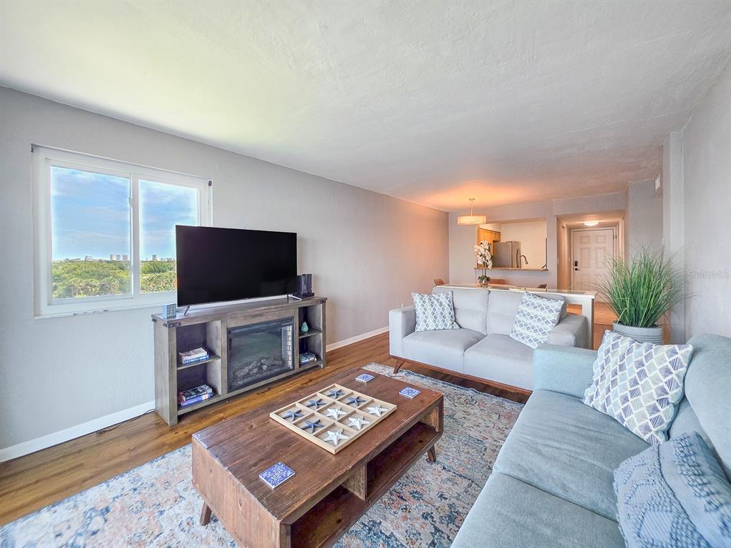 A living room features a fireplace media console, a coffee table, and two gray sofas — 145 N HALIFAX AVENUE UNIT 711, DAYTONA BEACH, FL