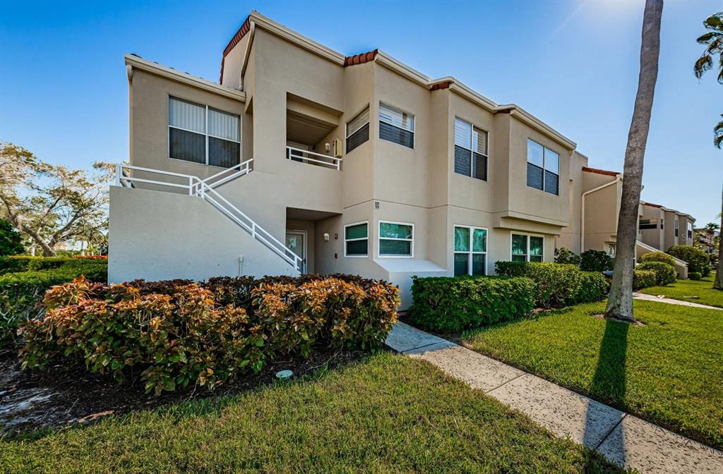 A two-story tan apartment building features an exterior staircase and surrounding landscaping — 6000 BAHIA DEL MAR CIRCLE UNIT 229, ST PETERSBURG, FL