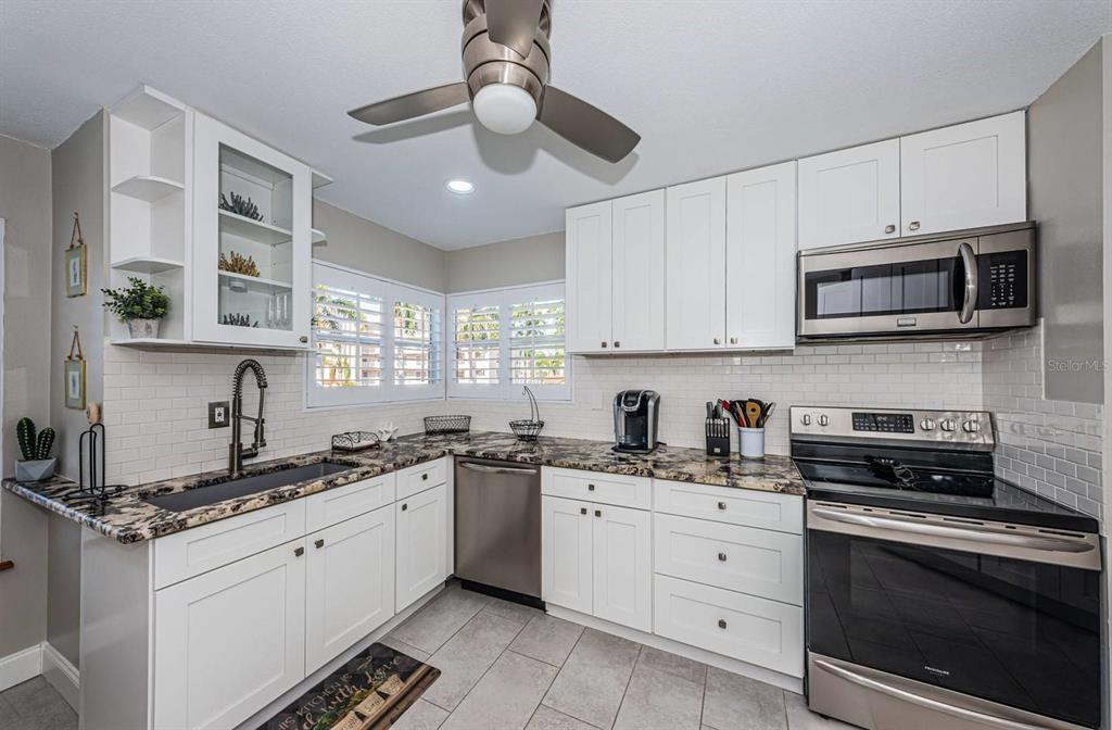 A kitchen features white cabinets, granite countertops, stainless steel appliances, and a subway tile backsplash — 6000 BAHIA DEL MAR CIRCLE UNIT 229, ST PETERSBURG, FL