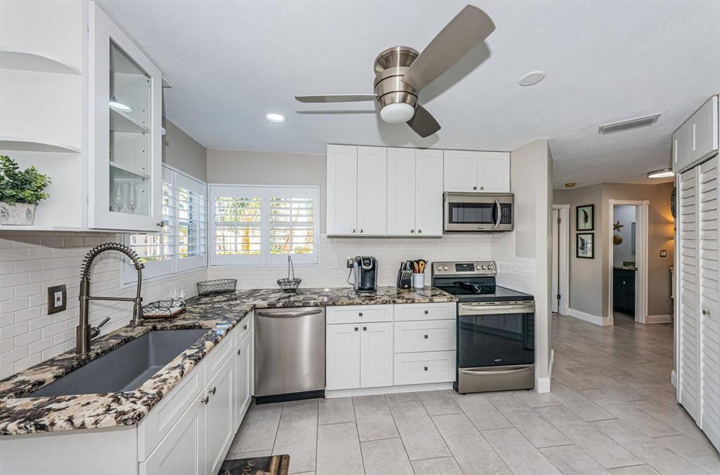 A kitchen features white cabinets, granite countertops, stainless steel appliances, and a ceiling fan — 6000 BAHIA DEL MAR CIRCLE UNIT 229, ST PETERSBURG, FL