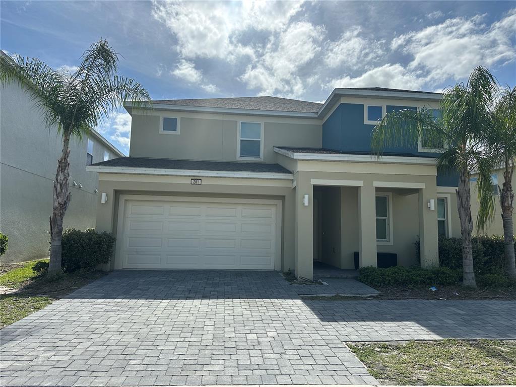 A two-story house with a paved driveway, a two-car garage, and two palm trees — 281 BALLO DRIVE, KISSIMMEE, FL