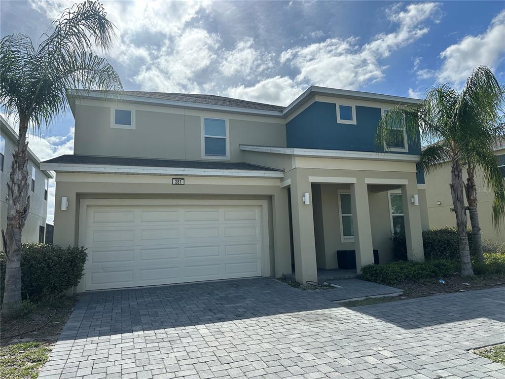 A two-story house with a beige stucco exterior, blue accent wall, and paved driveway — 281 BALLO DRIVE, KISSIMMEE, FL