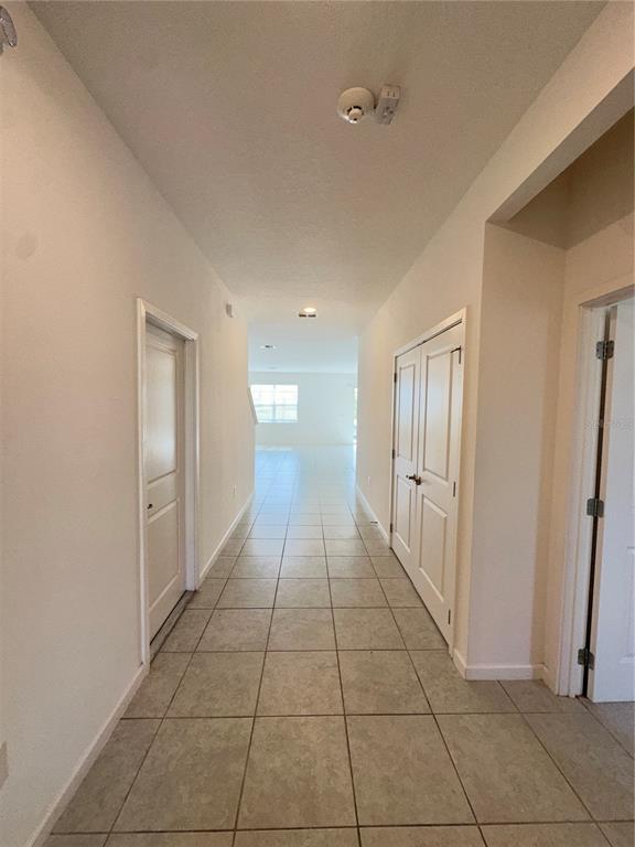 A tiled hallway leads toward a bright, open living area with two closed doors — 281 BALLO DRIVE, KISSIMMEE, FL