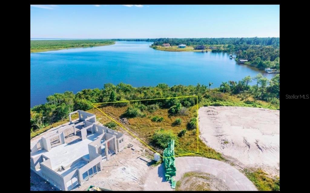 An aerial view shows a vacant, triangular waterfront lot next to a house under construction — 9488 ST MARYS COURT, PORT CHARLOTTE, FL