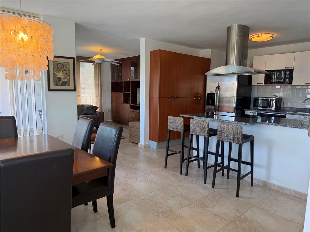 A dining area and kitchen with a breakfast bar, stainless steel appliances, and tile flooring — Apt B-205 COND. HARBOUR POINTS, HUMACAO, PR