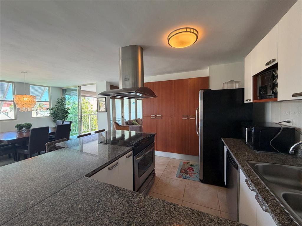 A kitchen with granite countertops, white cabinets, and a stainless steel range hood — Apt B-205 COND. HARBOUR POINTS, HUMACAO, PR