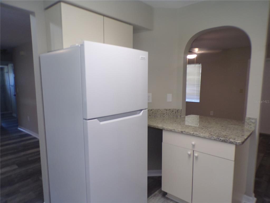 A white refrigerator stands next to a kitchen cabinet with a granite countertop — 1088 MELVILLE ROAD UNIT A, PUNTA GORDA, FL