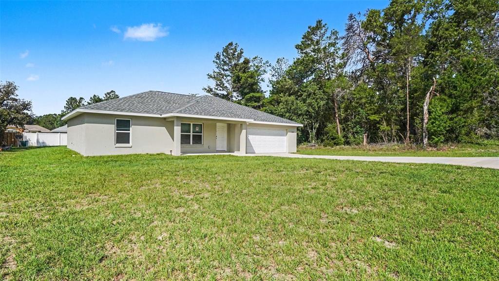 A single-story house with a light-colored stucco exterior and a two-car garage — 5360 SW 164TH STREET ROAD, OCALA, FL