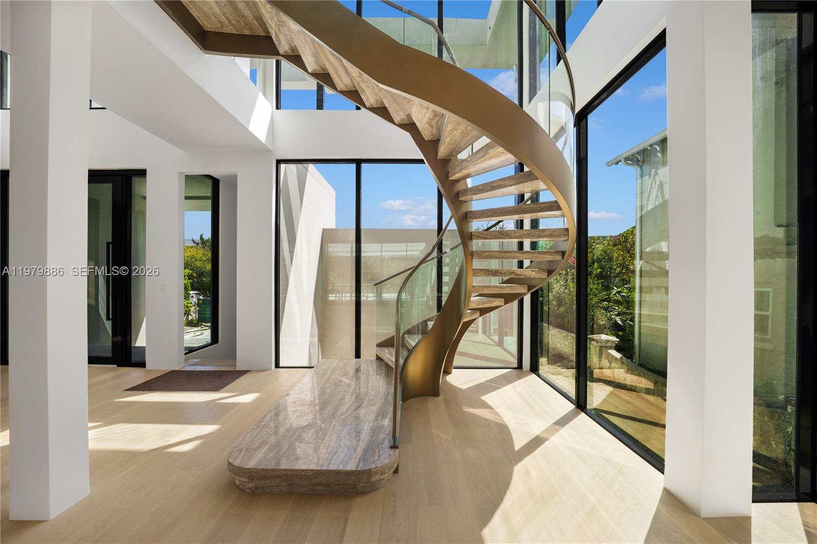 A modern interior features a sculptural spiral staircase with wood treads and glass railings — 2094 Prairie Ave, Miami Beach FL 33139, MIAMI BEACH, FL