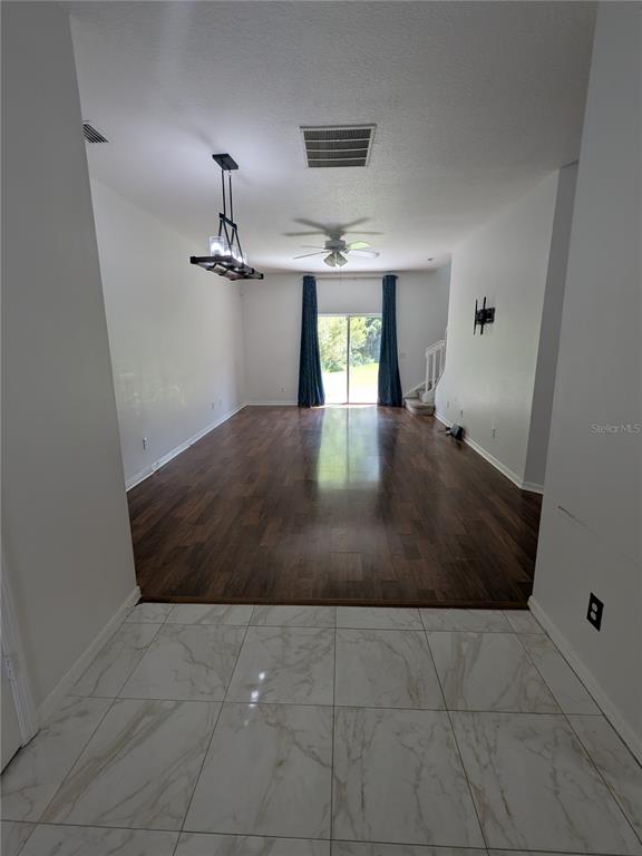 A long room with dark wood flooring transitions to white marble tile in the foreground — 20405 HARVEST OAK COURT, TAMPA, FL