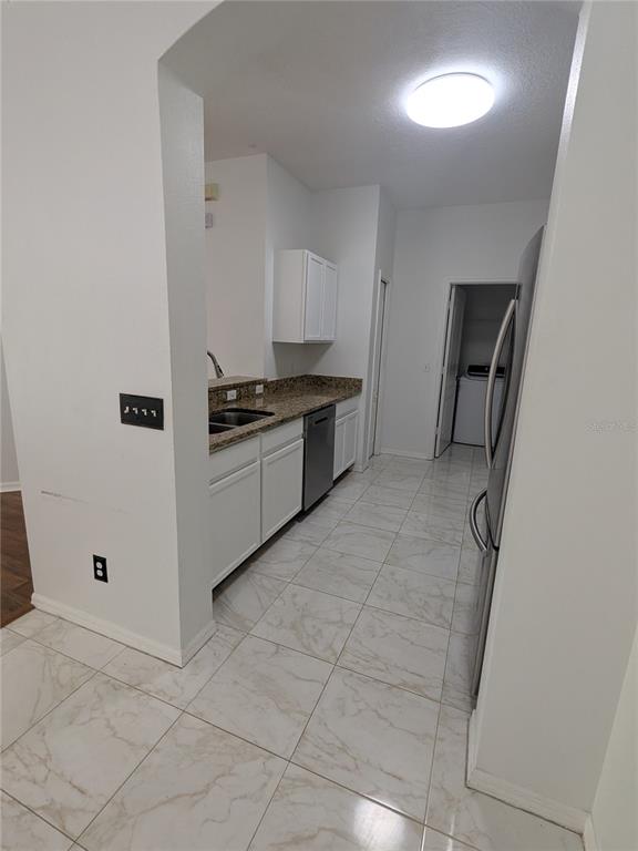 A kitchen features white cabinets, granite countertops, stainless steel appliances, and light-colored tile flooring — 20405 HARVEST OAK COURT, TAMPA, FL