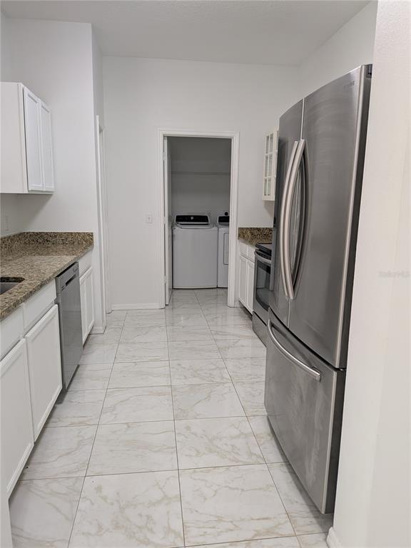 A kitchen features white cabinets, granite countertops, stainless steel appliances, and light-colored tile flooring — 20405 HARVEST OAK COURT, TAMPA, FL