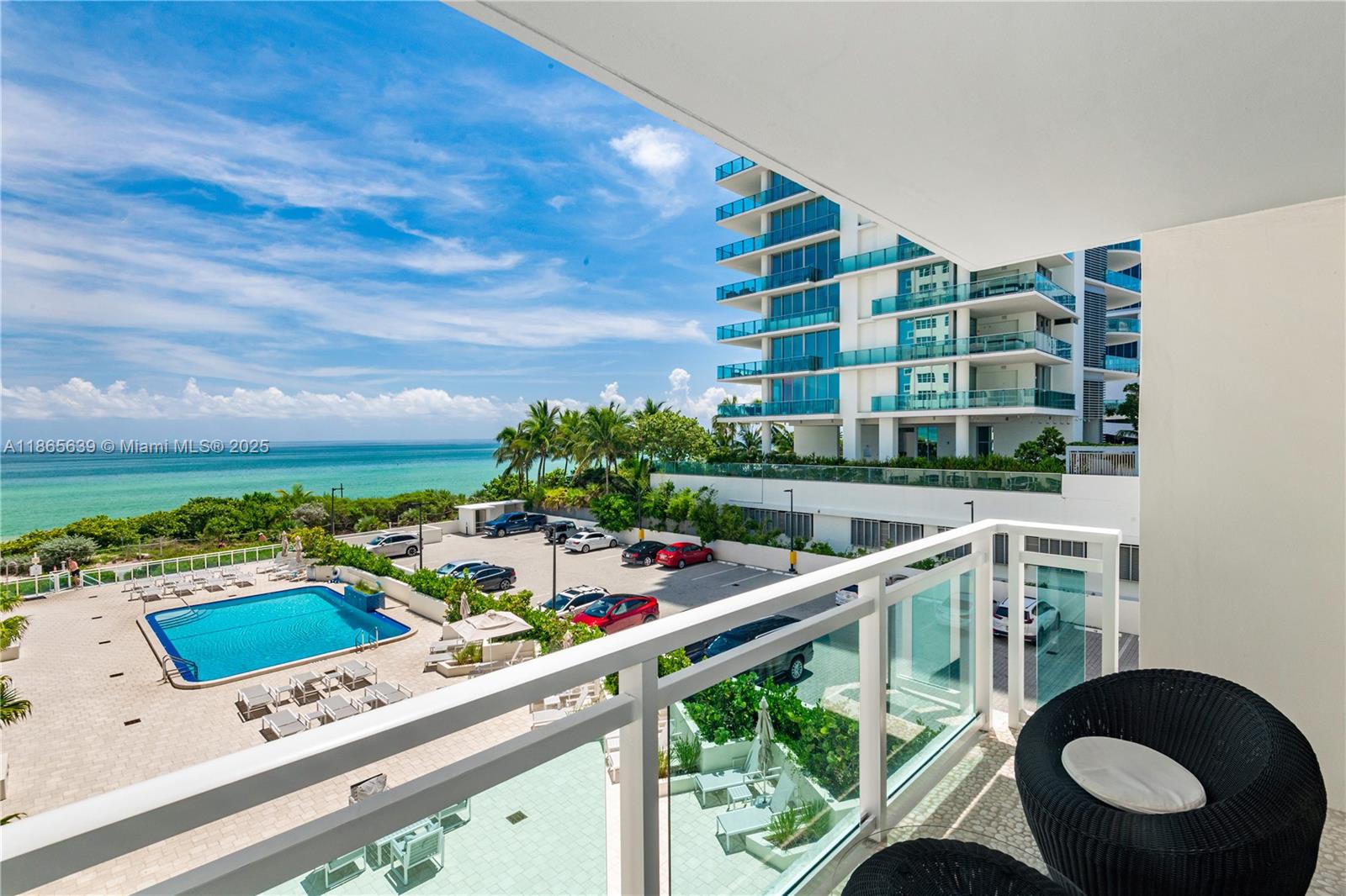 A balcony overlooks a swimming pool, a parking lot, and the ocean — 6917 Collins Ave # 511, Miami Beach FL 33141, MIAMI BEACH, FL