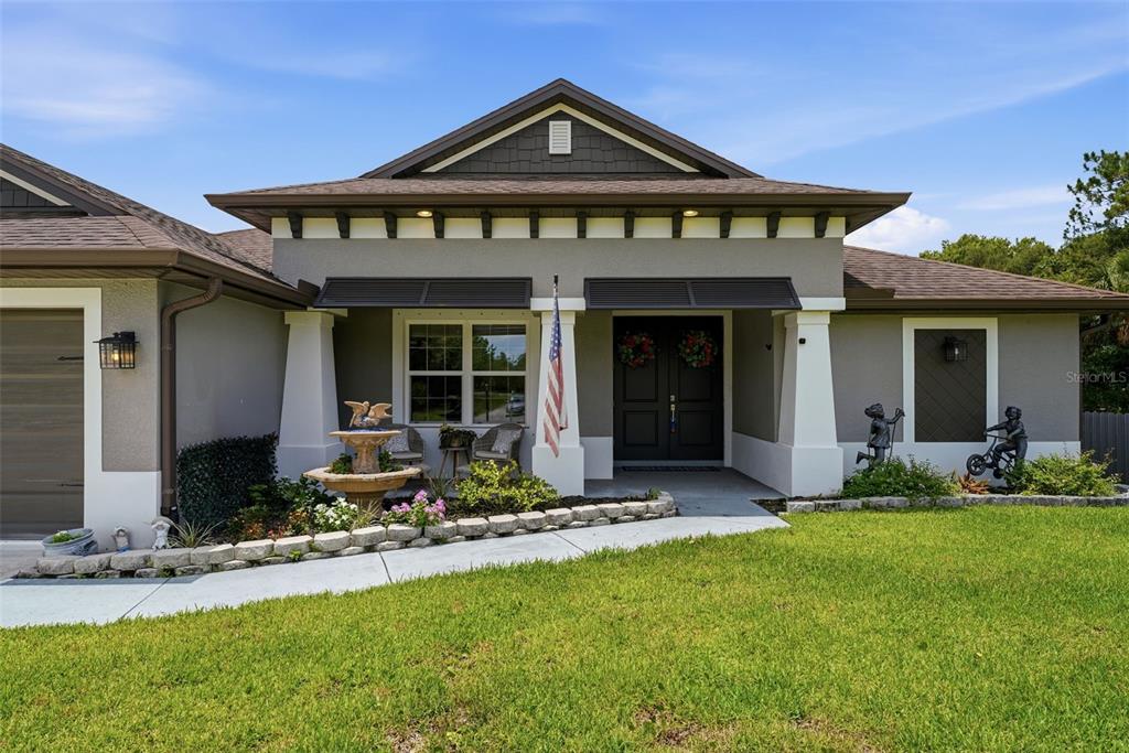 The exterior of a single-story house features a covered entryway, a fountain, and landscaping — 6755 TROPICAIRE BOULEVARD, NORTH PORT, FL