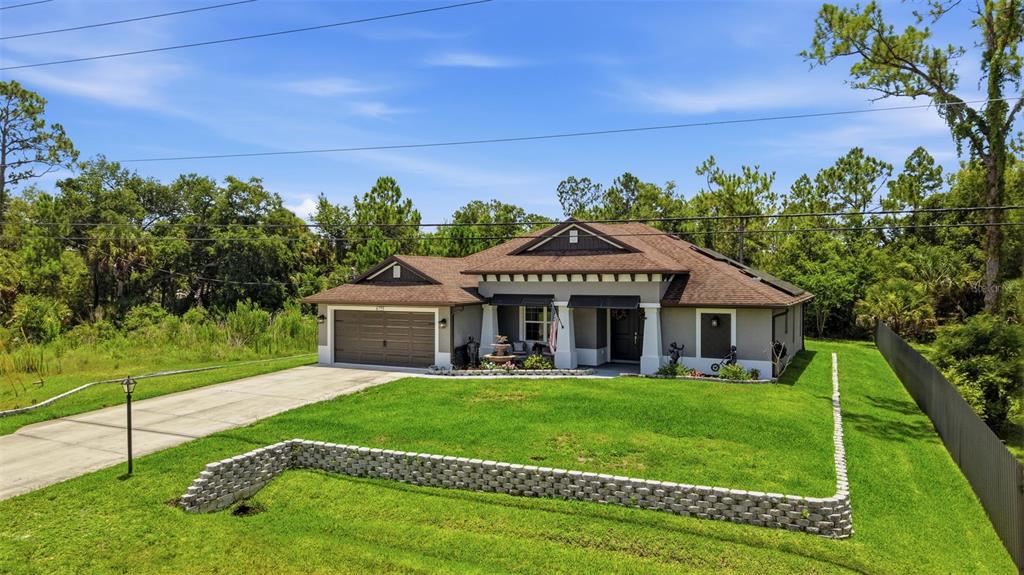 A single-story house with a brown roof, gray exterior, and a stone retaining wall — 6755 TROPICAIRE BOULEVARD, NORTH PORT, FL