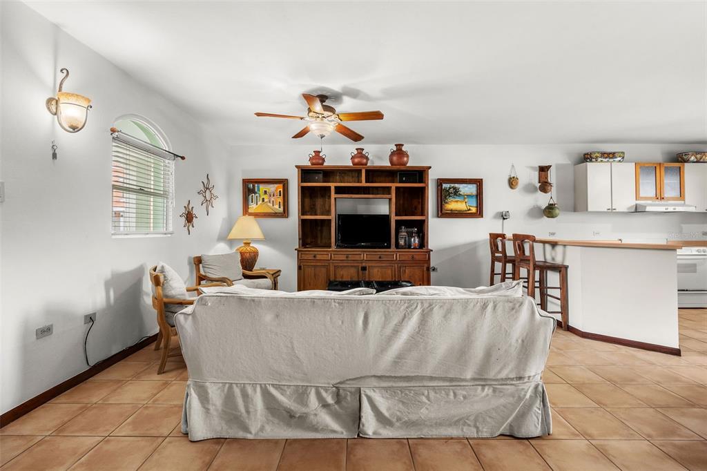 A living room with tile floors, a wooden entertainment center, and an open kitchen area — 195 CANDELERO DRIVE UNIT 6232, HUMACAO, PR
