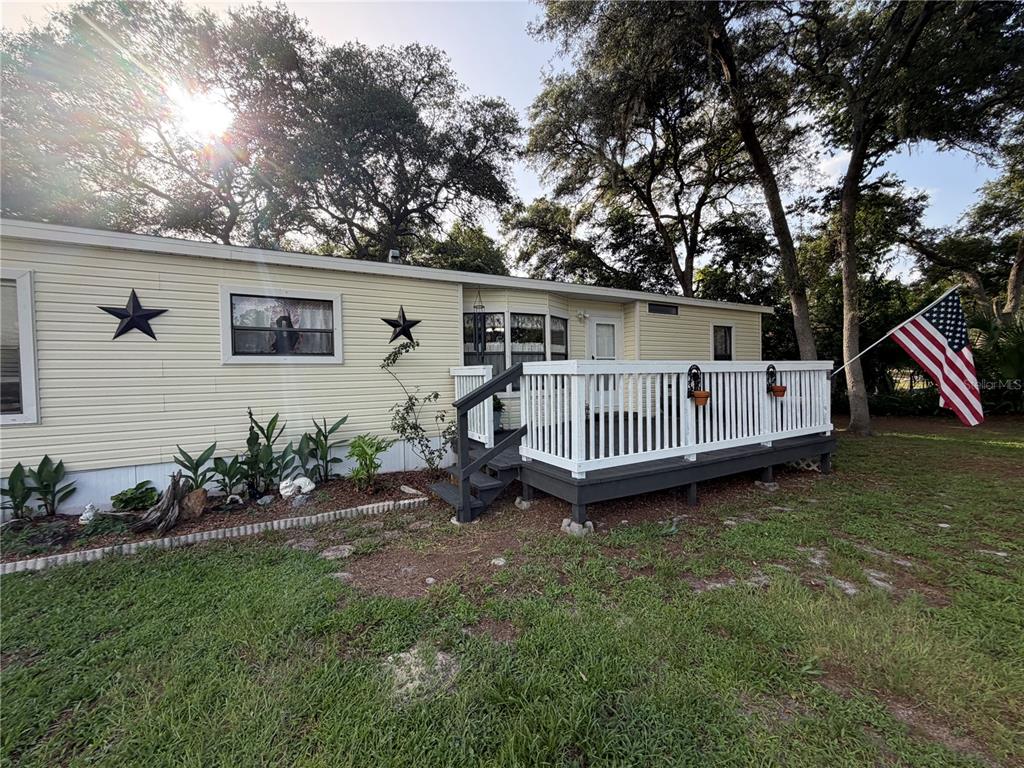 A yellow mobile home features a white wooden deck and an American flag in front — 40235 OVERLOOK DRIVE, EUSTIS, FL